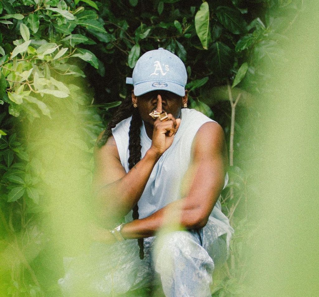 Photo Young Chang Mc accroupi entouré de verdure