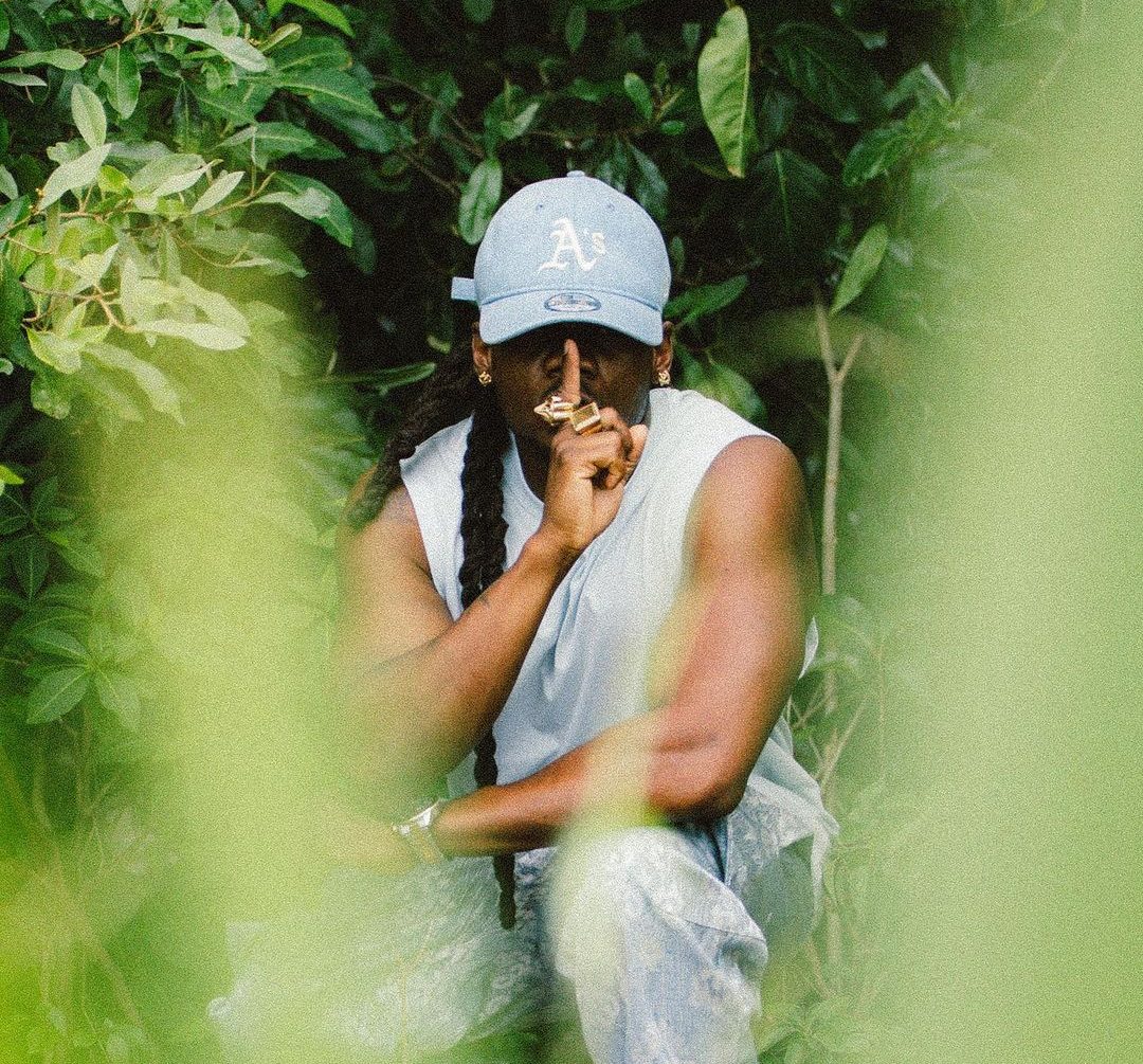 Photo Young Chang Mc accroupi entouré de verdure